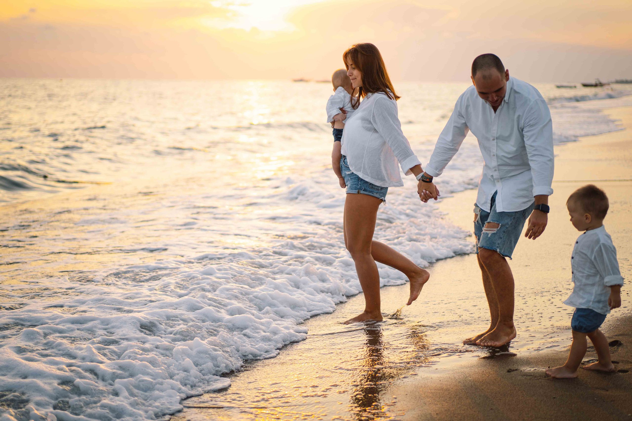 Happy family having fun playing beach in summer vacation on the beach. Happy family and vacations concept. Seascape at sunset with beautiful sky. Family on the beach.